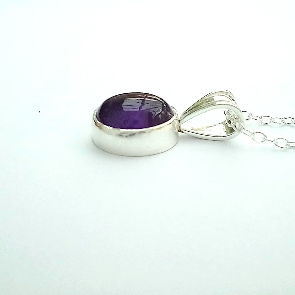 Side view of cabochon amethyst pendant with bail and chain.